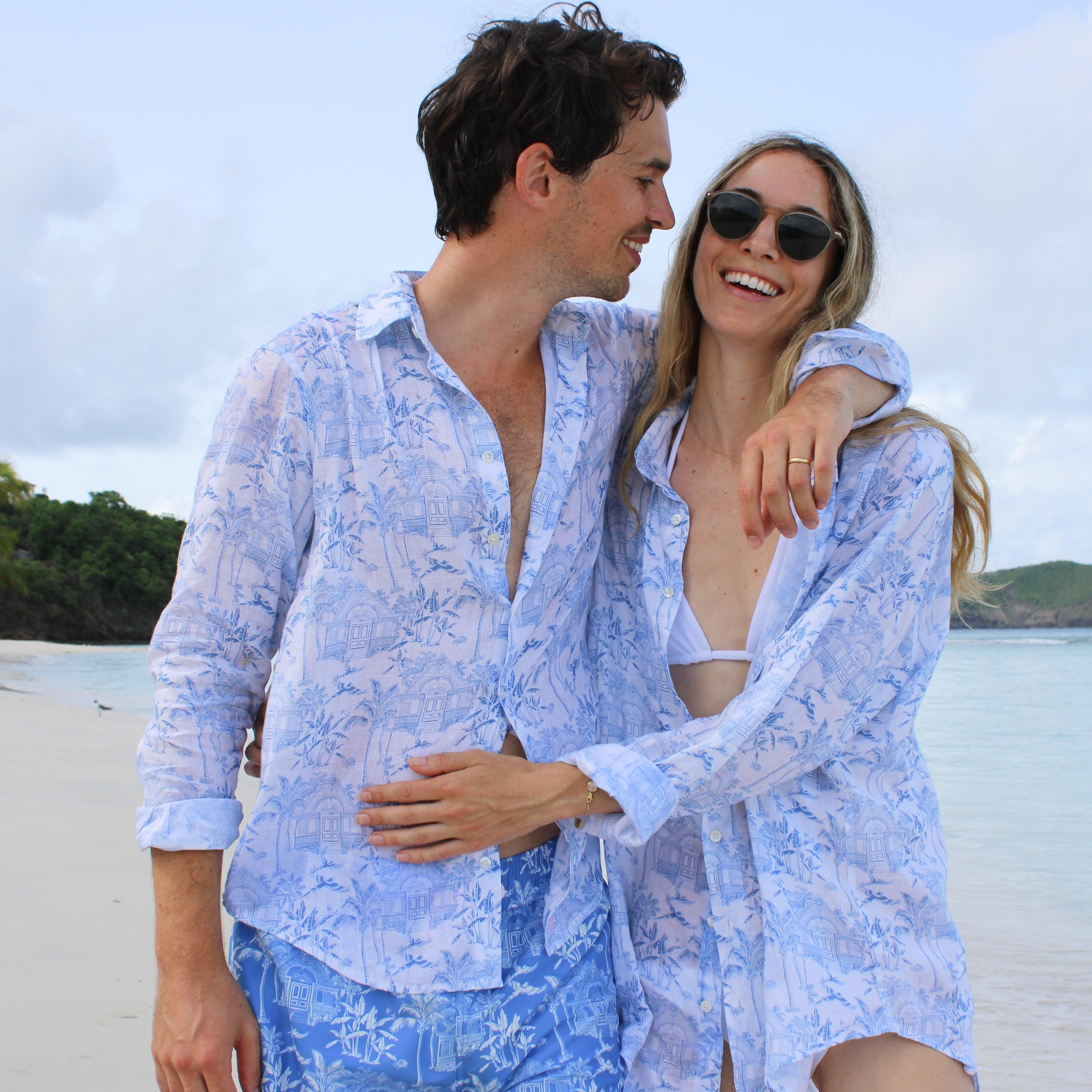 Smiling couple in matching blue toile shirts on a tropical sandy beach
