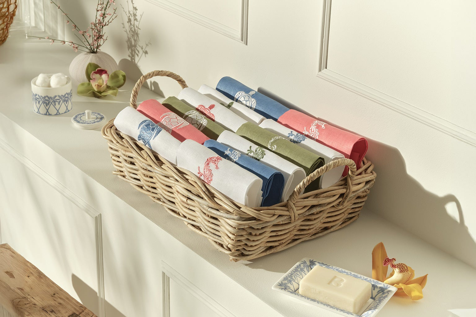 New in - Coloured linen hand towels with embroidered seahorse, palm, and turtle motifs displayed in Pink House Mustique showroom.