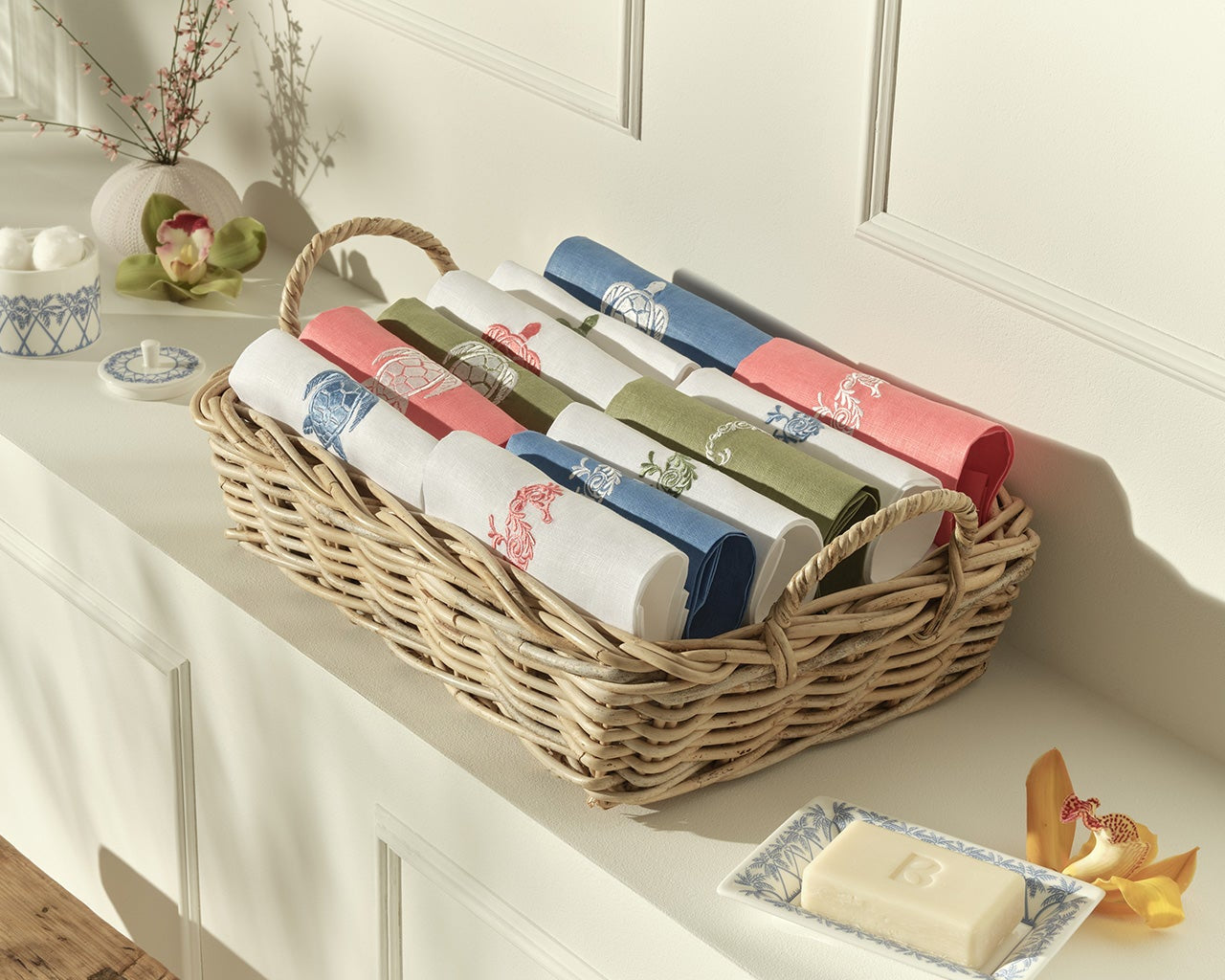New in - Coloured linen hand towels with embroidered seahorse, palm, and turtle motifs displayed in Pink House Mustique showroom.
