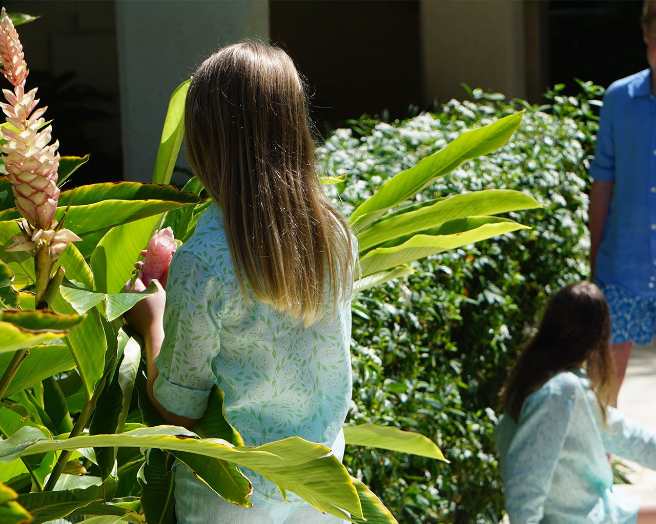 Children wearing Pink House kids linen shirts and swim shorts in a tropical garden, now on sale in the outlet