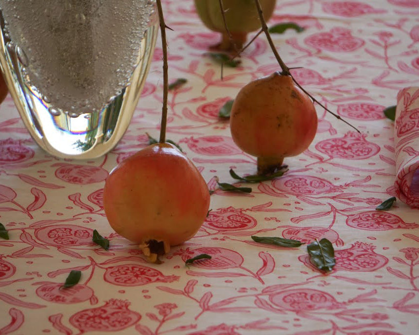 Pomegranates in a vase table decorations on floral print tablecloth by British fashion and interiors designer Lotty B Mustique
