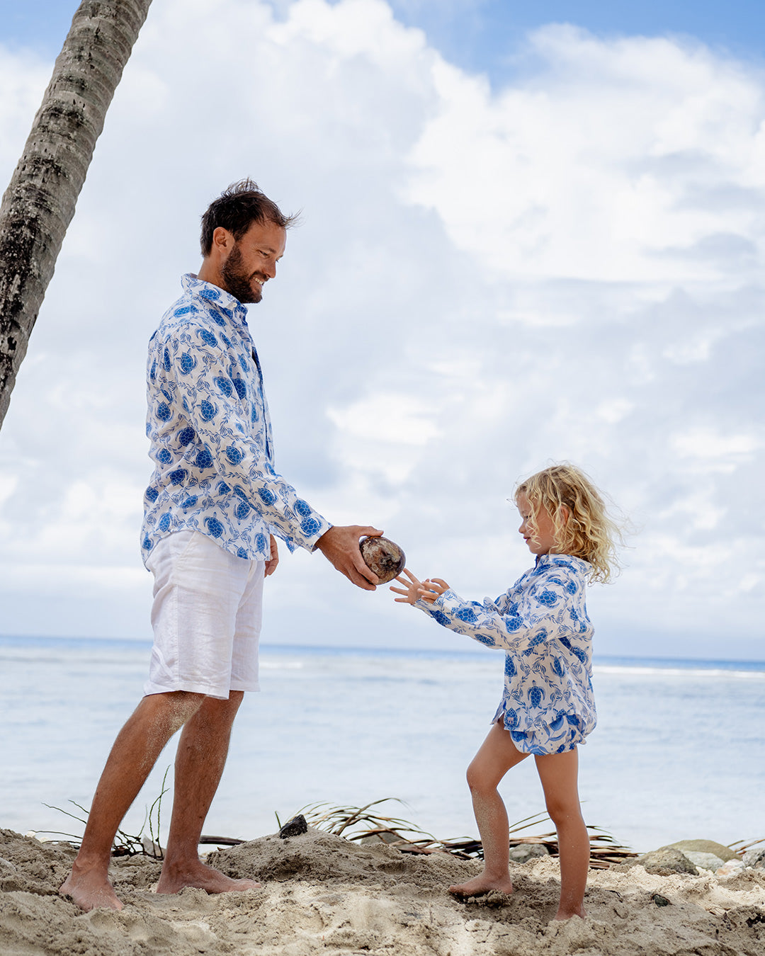 father and child on beach in matching linen shirt