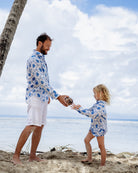 father and child on beach in matching linen shirt