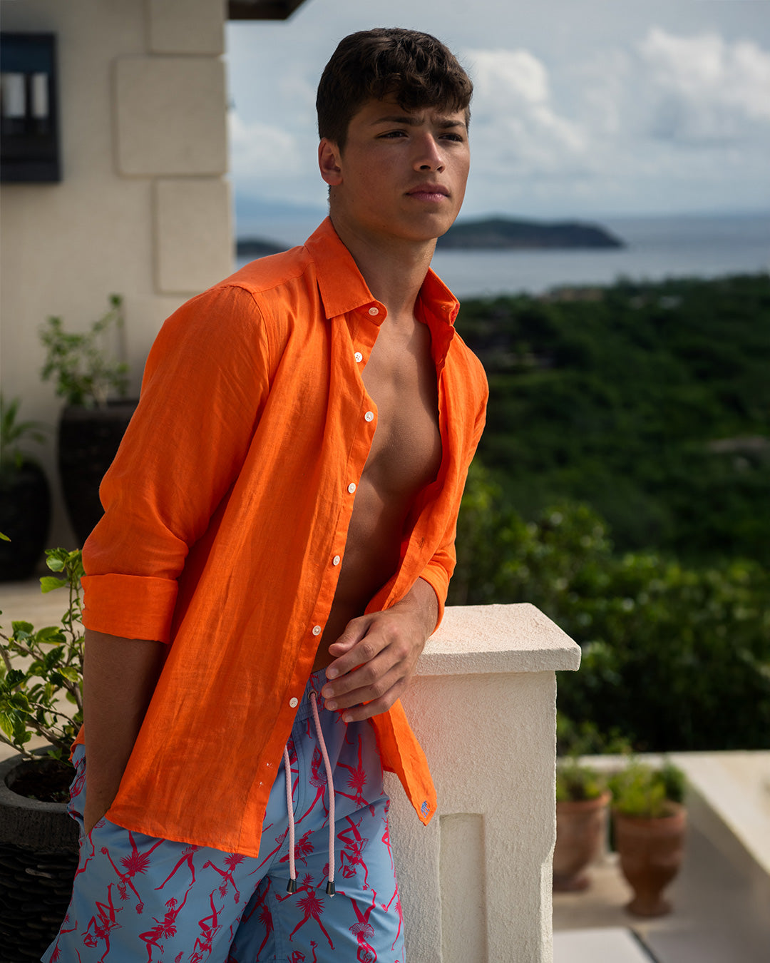 Pink House men’s orange pure linen shirt worn open with patterned swim shorts, relaxed luxury Caribbean resort styling
