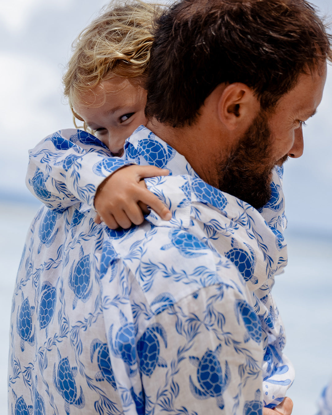 child and father in matching linen shirt with turtle print on