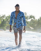 Men’s Iguana print linen shirt in blue spruce green with black floral swim shorts, island resortwear by Pink House Mustique.