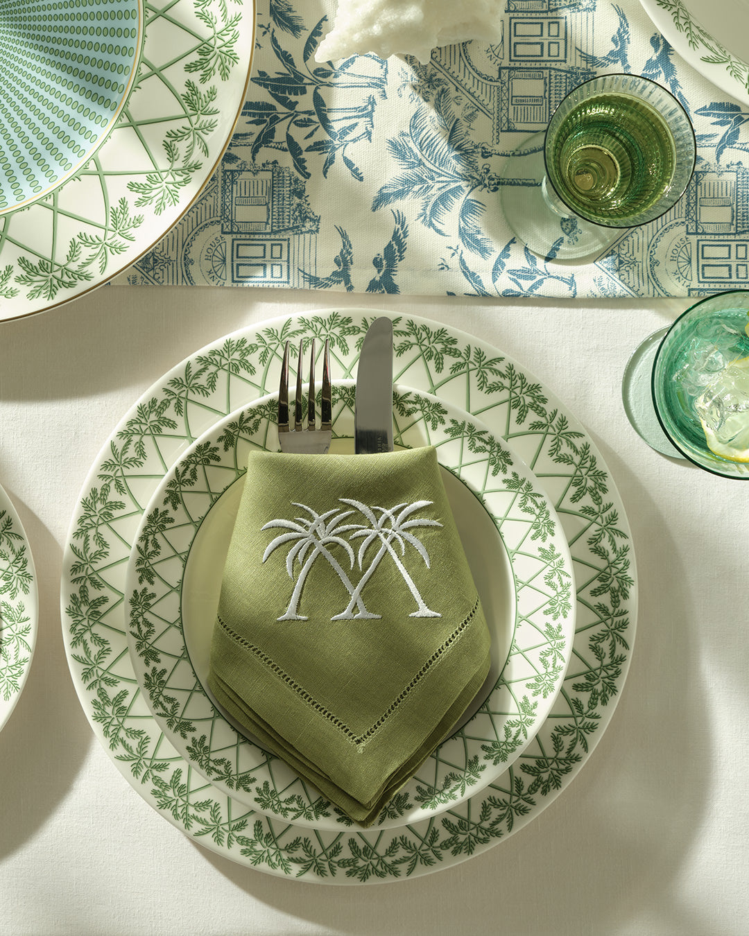 Embroidered linen napkin with crossed palms on rimmed bowl stacked on 30cm fine bone china dinner plate in Palms Sage Green.