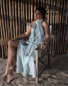 Chic holiday style sitting on Dolly beach, Mustique Island in the linen Trinny dress in green Pangolin pattern.