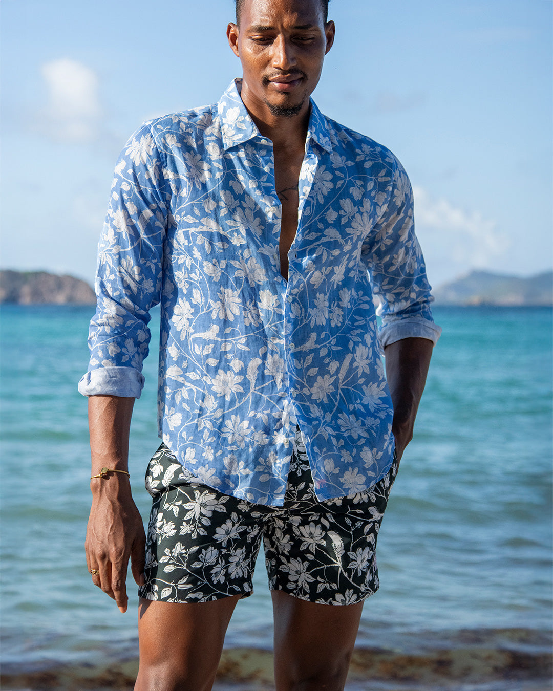 Men’s Iguana Spruce swim shorts styled with blue linen shirt — sustainable resort wear by Pink House Mustique.