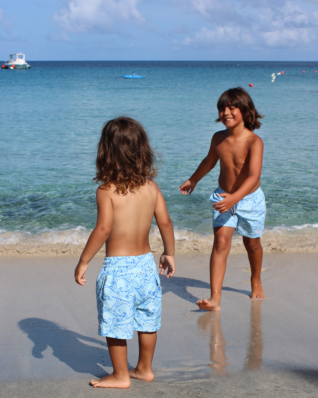 two young children in the sea with matching swim shorts