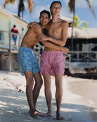 two men in swim shorts on a beach