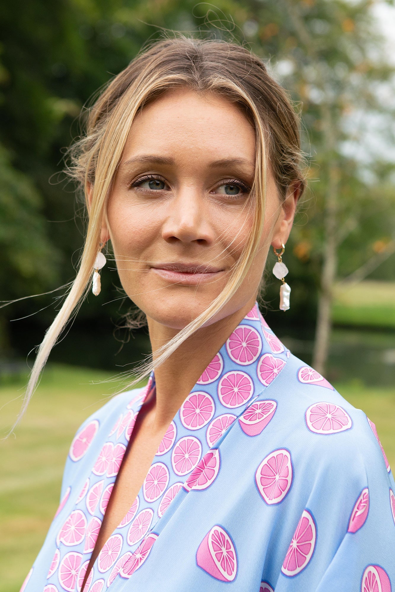 Zoom on Lotty B Jade Poncho neckline and collar in Lime Tree print – silk crepe-de-Chine fabric with vibrant pink citrus slice pattern, styled with statement pearl earrings.