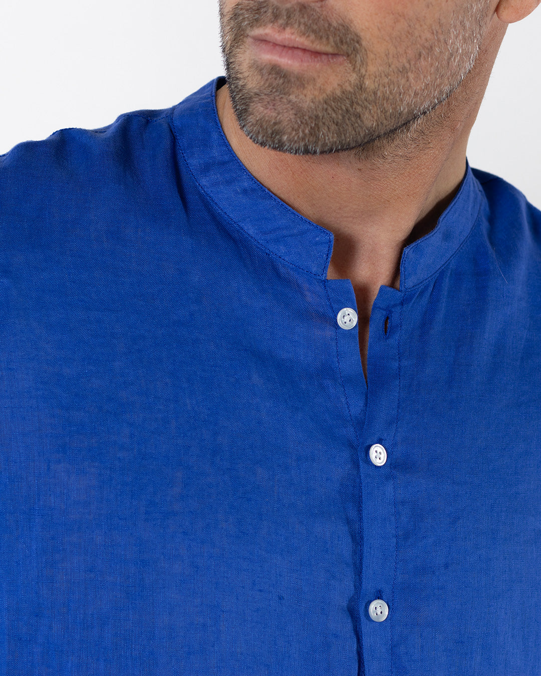 Close up of mens dazzling blue linen shirt with collarless grandad Nehru collar and button front, lightweight summer fabric