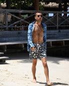 Man wearing Iguana Blue & Spruce linen shirt with dark green leaf print at Basil’s Bar, Mustique.