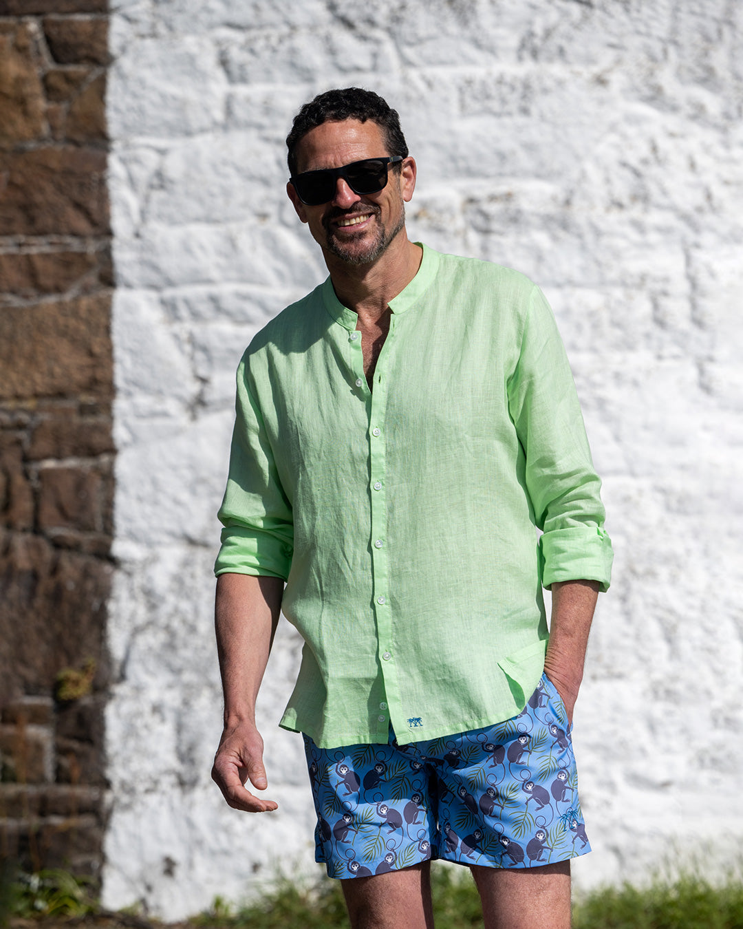Mens pistachio green linen grandad collar shirt with buttoned cuffs styled with monkey plum swim shorts