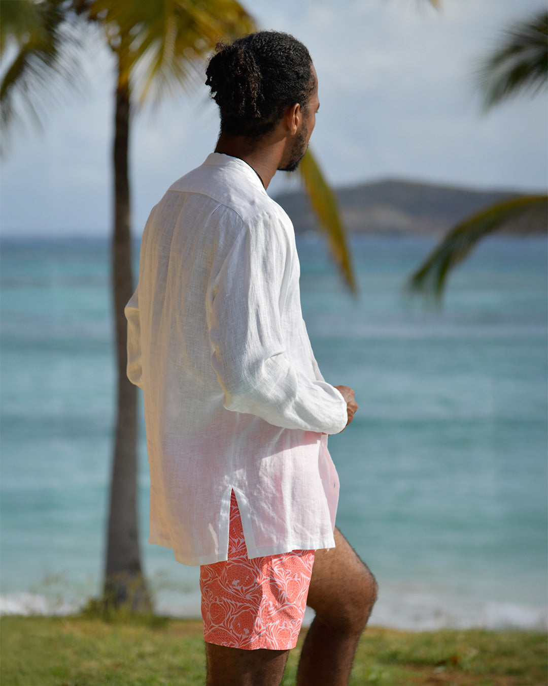 Mens white linen collarless shirt back view on beach with swim shorts, relaxed resort style with Nehru collar
