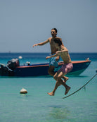 two men jumping from a boat in matching swim shorts