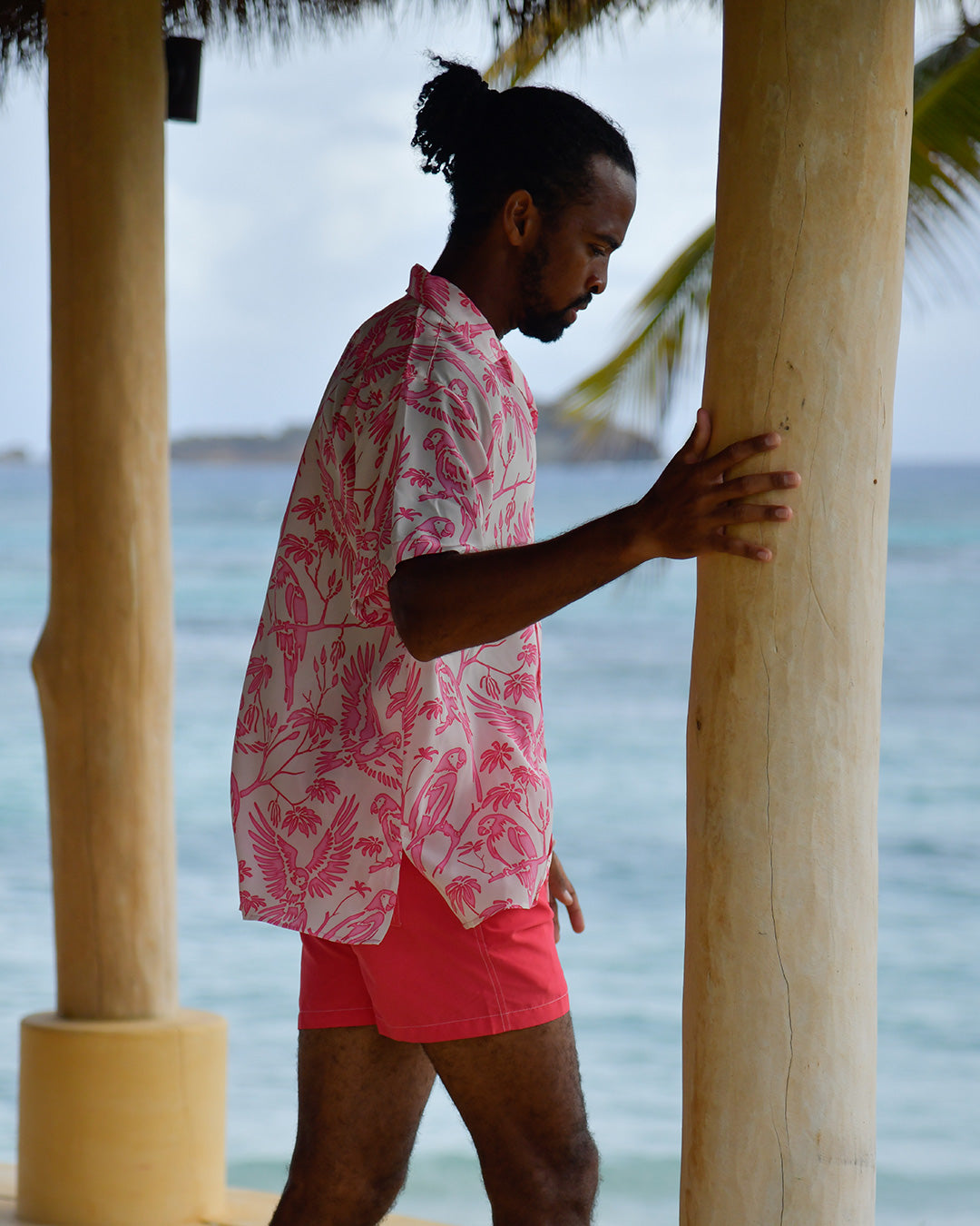 Side profile of men's Parrot Pink silk Festival Shirt overlooking the Caribbean Sea in Mustique