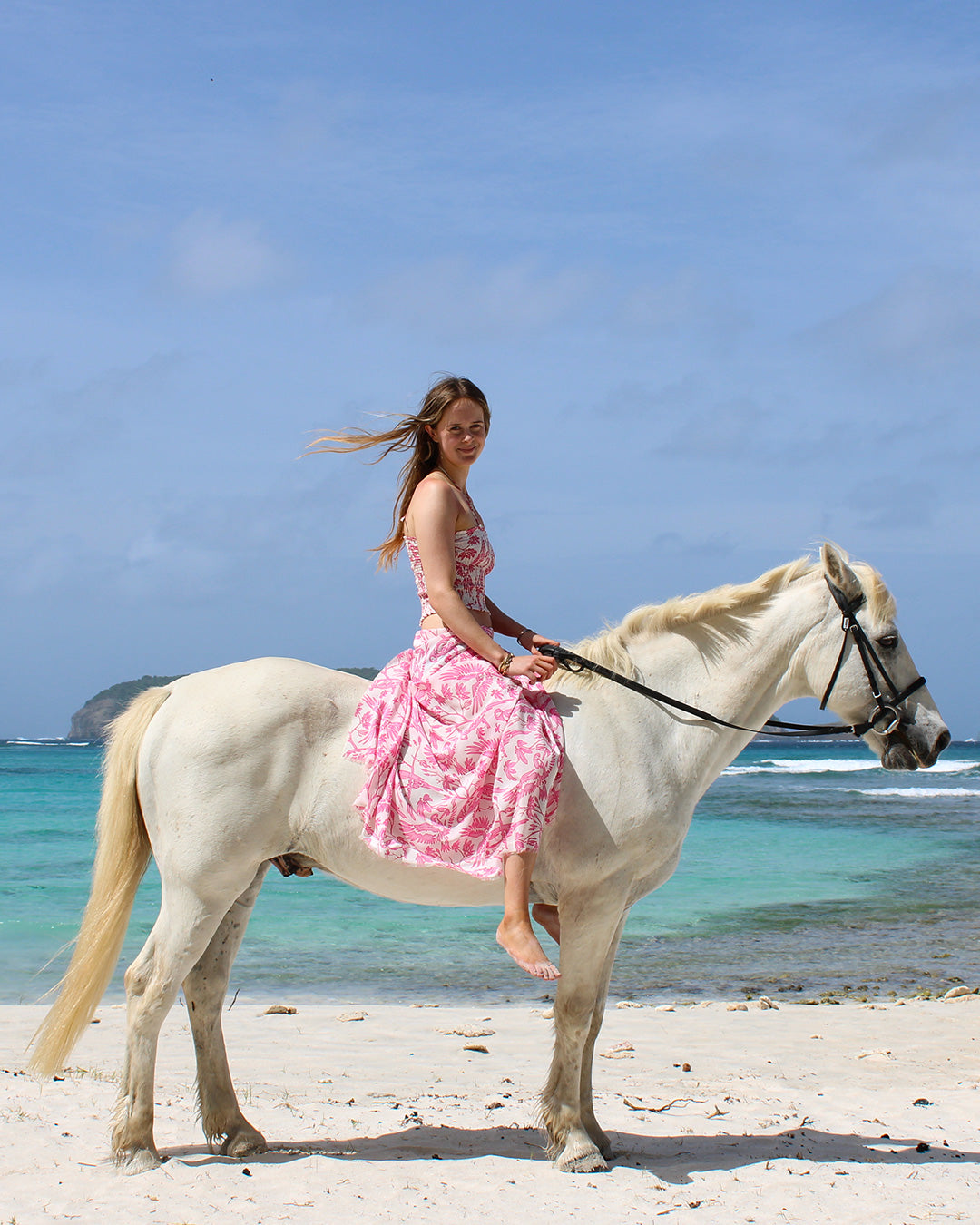 Luxury silk sarong in Parrot Pink worn with ruched bandeau top on horseback at Lagoon Bay, Mustique island