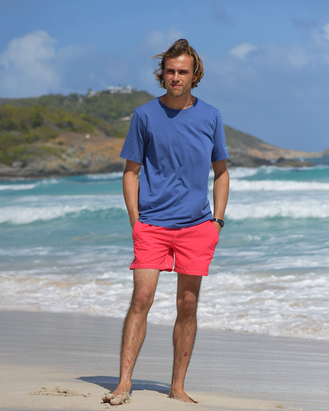 Pablo wearing Pink House navy T-shirt and faded red swim shorts on Pasture Bay beach, Mustique Island