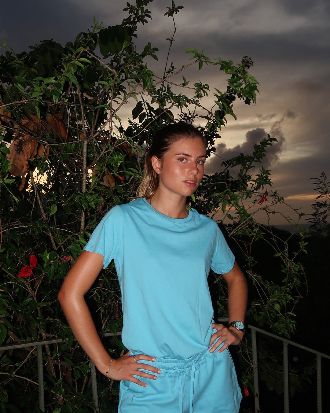 Pink House pale blue pure cotton T-shirt worn at dusk, relaxed tropical Mustique beach essentials look