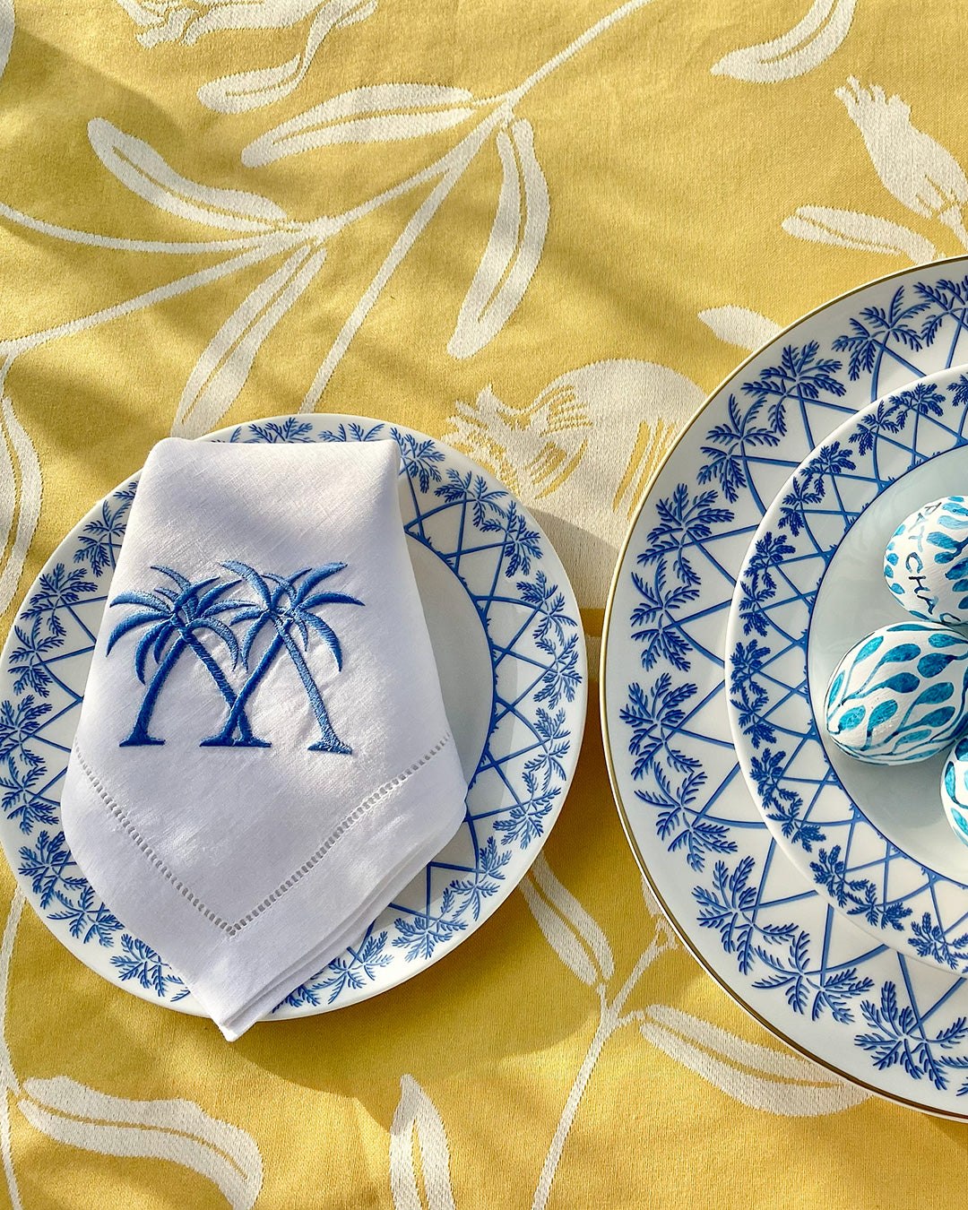 Spring tablescape with Palms Azure Blue fine bone china plates styled on Pomegranate Yellow tablecloth.