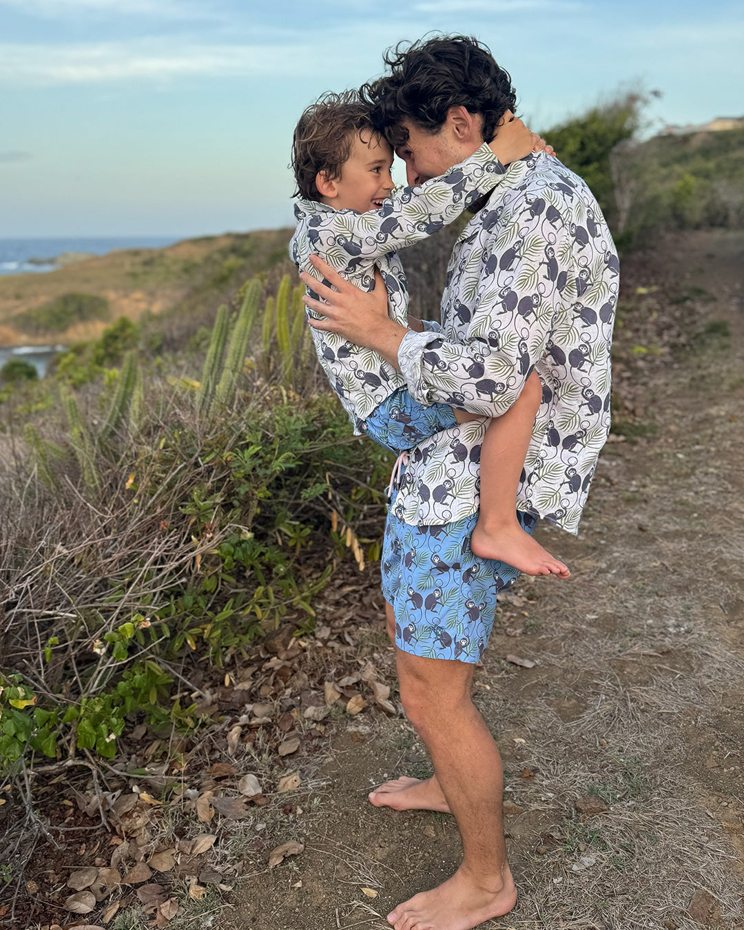 Father and child sharing a hug in matching Monkey & Palms linen shirts, Pink House mini-me family style