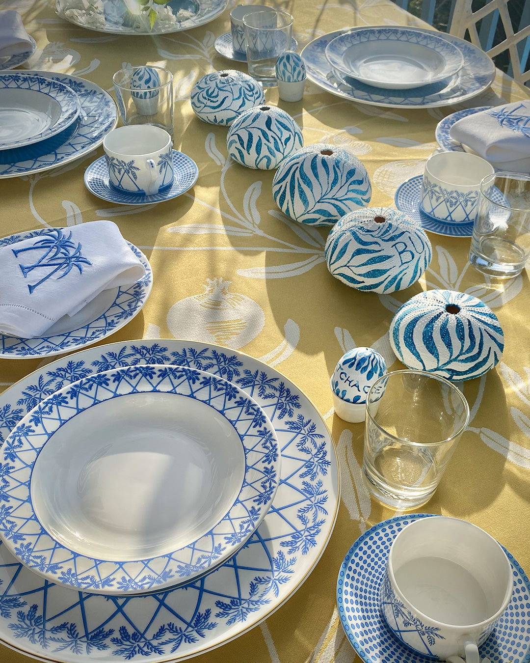 Tropical table setting with fine bone china Palms Azure Blue rimmed bowl and Azure Blue accents on yellow tablecloth.