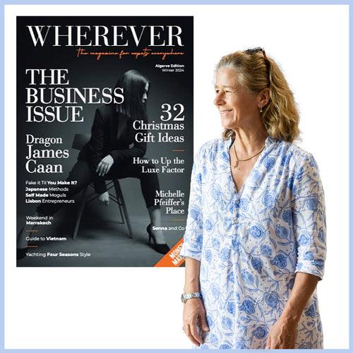 Smiling woman in patterned dress standing beside WHEREVER business magazine cover