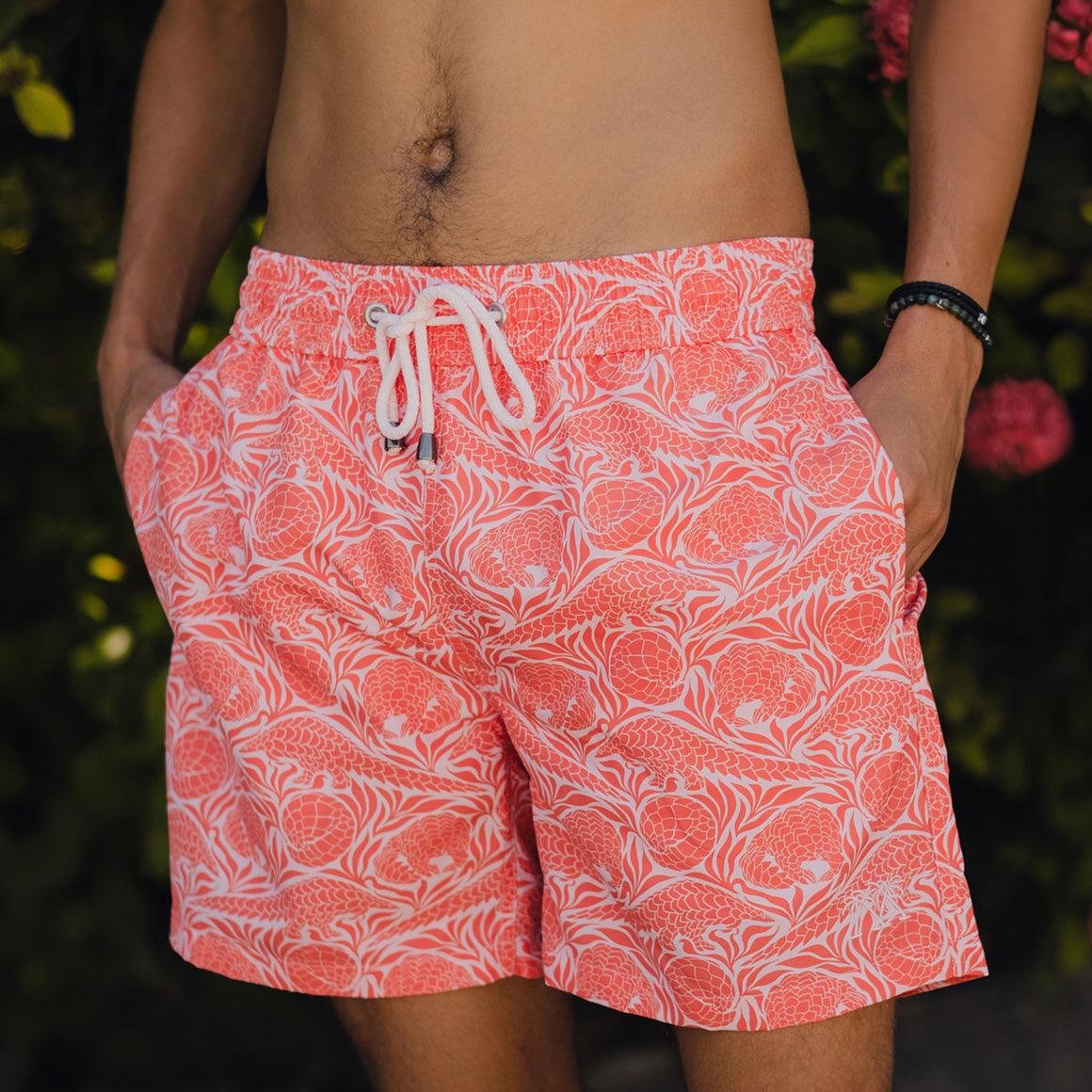 person wearing swim shorts in orange with pangolin print