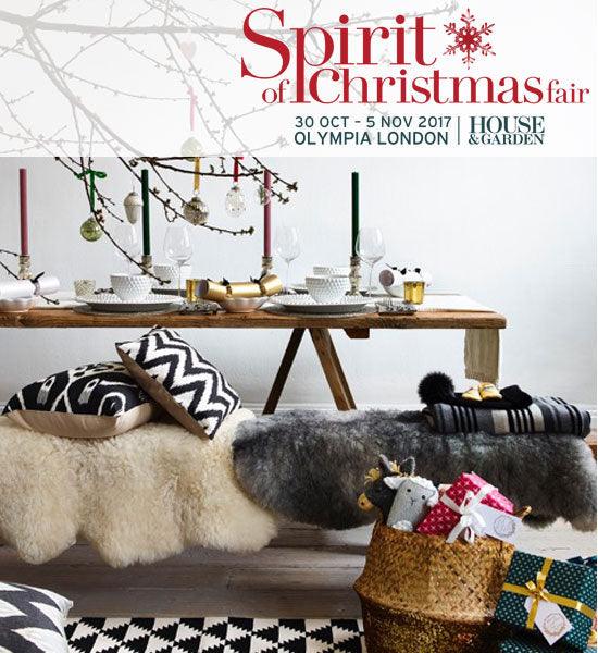 Christmas fair table setting with candles, gift basket, and cozy decor at Olympia London
