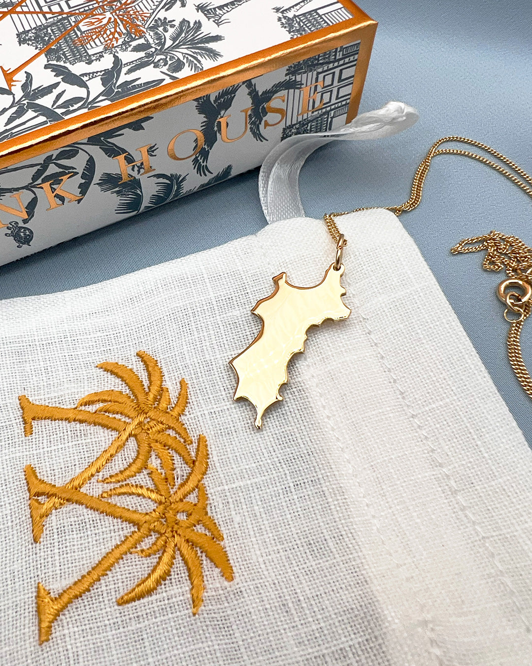 Close up 18 carat gold Mustique island pendant necklace with Pink House Mustique gift box and pouch