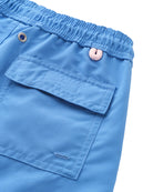 Close-up of blue swim trunks shorts with a pocket and button on a white background