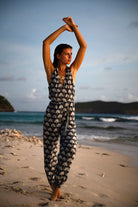 Woman wearing black and white Fan Palm silk jumpsuit walking barefoot on the beach