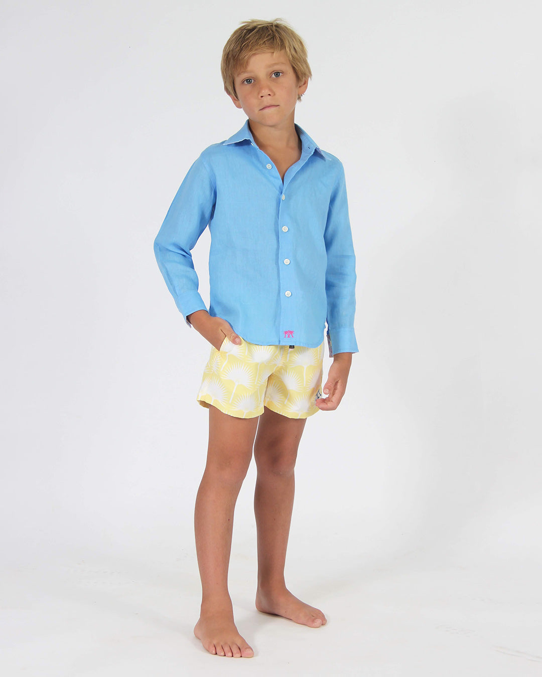 Boy wearing Fan Palm Yellow swim shorts with French Blue linen shirt in studio
