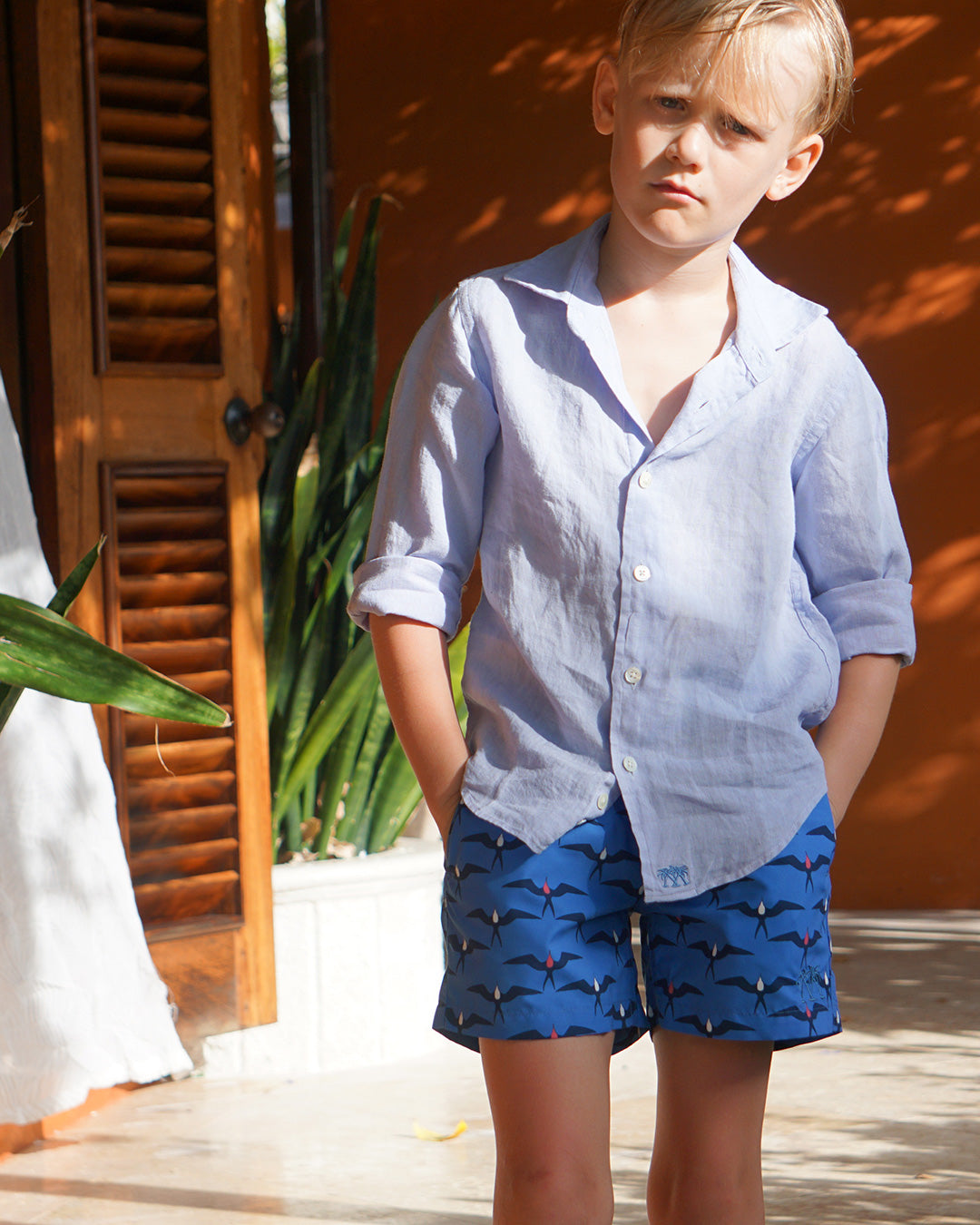 Boy wearing Frigate Bird Blue swim shorts with Azul Blue linen shirt at a villa in Mustique