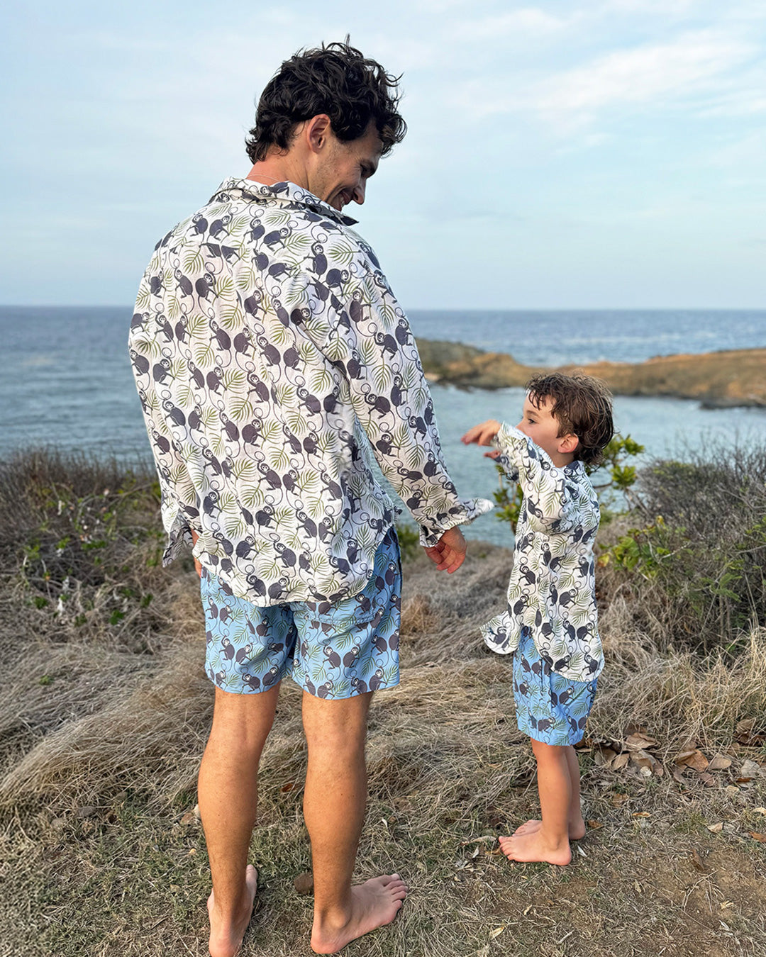 Father and son in matching Monkey & Palms linen shirts and swim shorts, coastal family mini-me style by Pink House Mustique