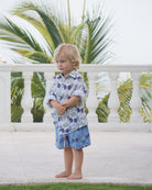 Unisex kids linen shirt in monkey and palms print, plum navy and green, styled for beach holidays by the sea