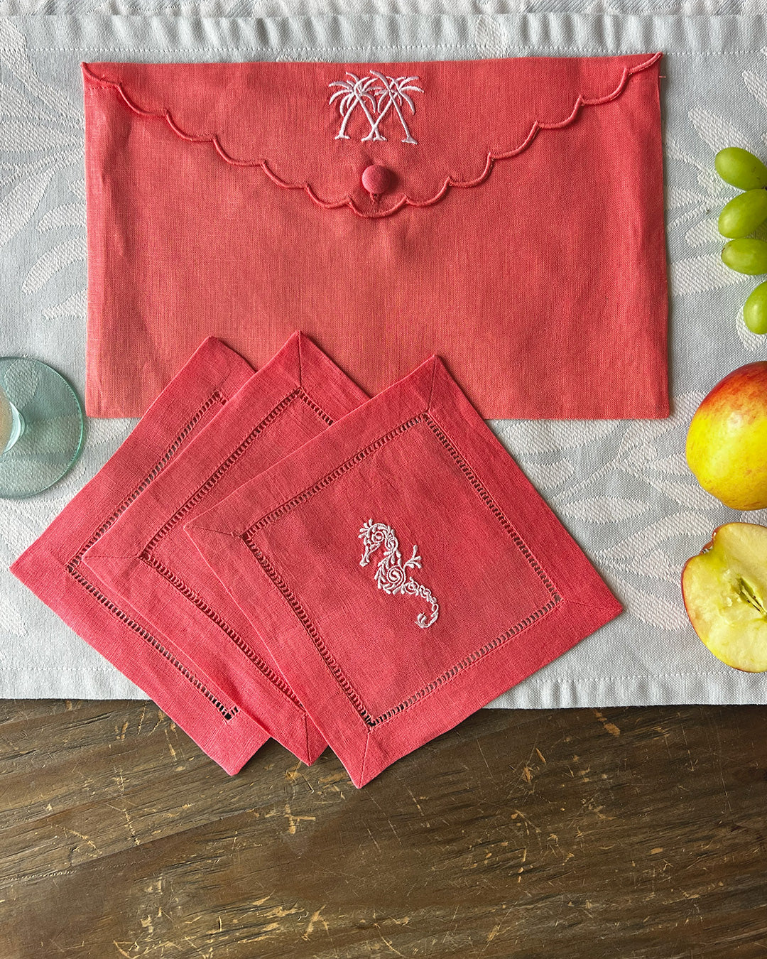 Coral pink linen cocktail napkins with seahorse embroidery and matching envelope case, by Pink House Mustique.