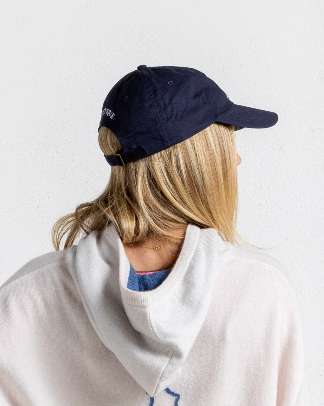 Mustique navy baseball cap with embroidery and strap closure, styled with soft hoodie for chic coastal casualwear.