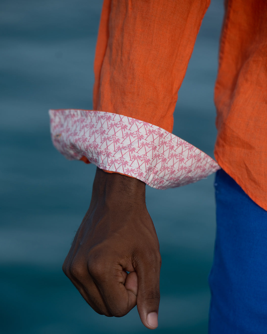 Detail of Pink House men’s linen shirt cuff in orange, lightweight fabric with refined finish for luxury resortwear
