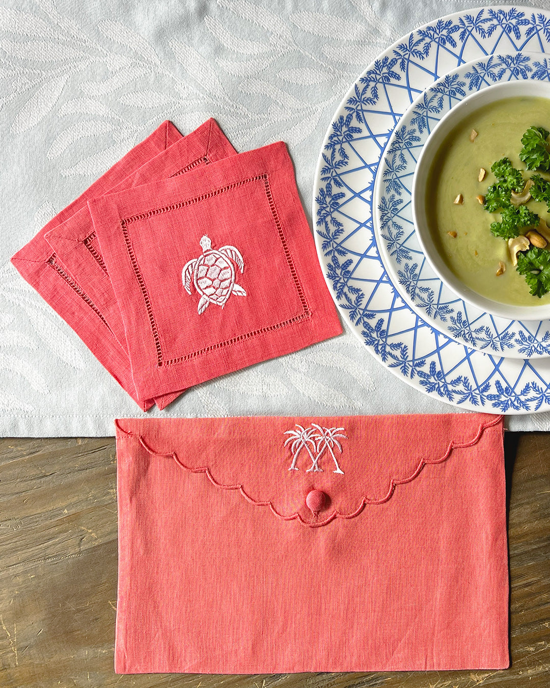 Embroidered linen gift bag in Palms Coral Pink styled with matching turtle embroidered cocktail napkins