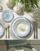Dining table setting with blue and white Palms patterned rimmed bowl on a dinner plate.