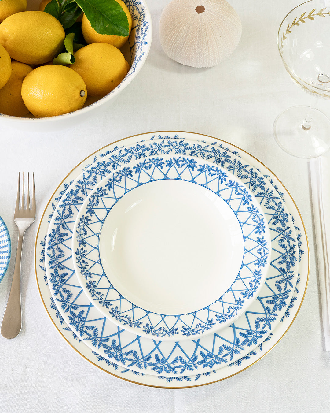 Luxury fine bone china Palms Azure Blue rimmed bowl and Azure Blue set arranged for a tropical dining table.