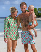 Family wearing matching Watermelon print resortwear and swim shorts on a Caribbean beach