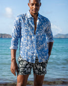 Men’s Iguana Spruce swim shorts styled with blue linen shirt — sustainable resort wear by Pink House Mustique.