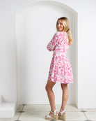 Silk CDC Amy dress in Parrot pink – tiered design and relaxed fit, shown from back angle with model looking over shoulder.