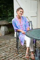 Smiling Nina in Lotty B Jade Poncho – tropical citrus print in pink and blue on pure silk, perfect for relaxed yet refined outdoor resort looks.