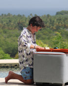 Kids monkey and palms linen shirt in plum navy and green, worn with matching swim shorts on tropical holiday