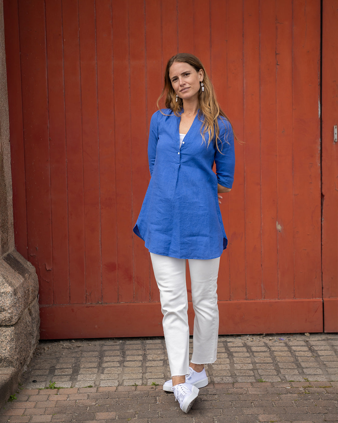 Model Hettie wearing a Sax Blue linen Decima dress over white trousers – versatile tunic-style dress for everyday or travel